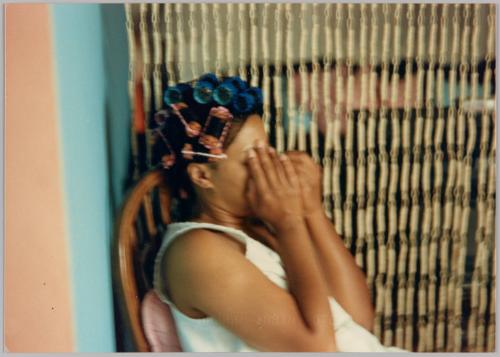 [Woman with curlers in her hair covering face with hands]
