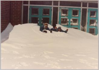 [Two man buried in pile of snow in front of doors]
