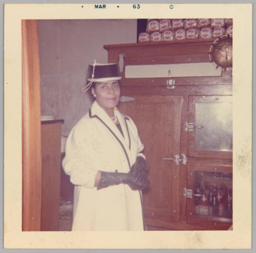 [Woman posing in white coat and black gloves and hat]
