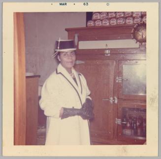 [Woman posing in white coat and black gloves and hat]
