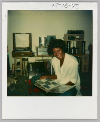 12-16-78 [Woman posing with photo album in hand]
