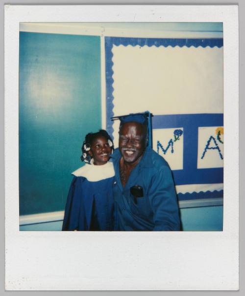 [Little girl in blue graduation gown posing with older man]
