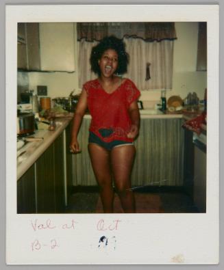 Val at B-2 Oct [illeg.] [Woman in red t-shirt and short bottoms standing in kitchen laughing]