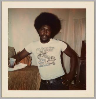 [Man standing inside with one hand on hip and other hand holding plastic cup, he is wearing a t-shirt that reads "I'll make you an offer you can't refuse"]