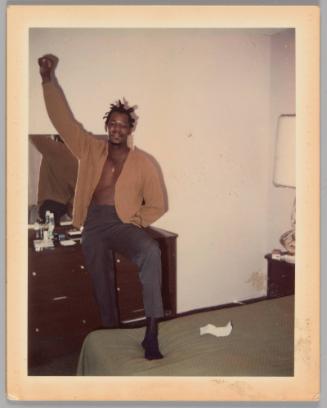 Johnnie Married 1970 [Man with one foot stepped up onto bed and one arm raised with his hand in a fist, dresser with mirror behind him]