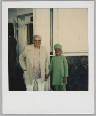 Mosque 1997 [Older woman in glasses and grey jacket holding hands with girl in double-breasted green coat and matching hat]