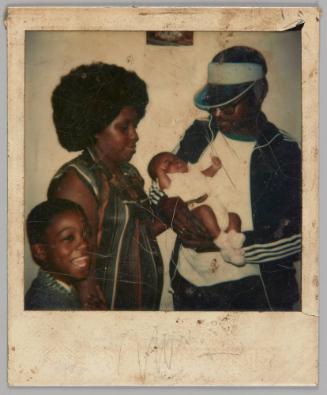 Dec 19 [Man in visor and blue track jacket holding squirming baby, to the left there is a boy laughing and a woman looking down at the baby]