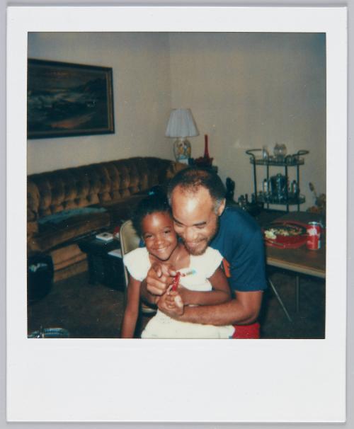 [Little girl smiling while being embraced by man in navy blue tshirt]