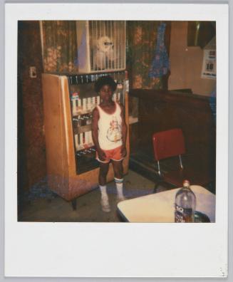 [Boy in basketball uniform standing in front of vending machine]