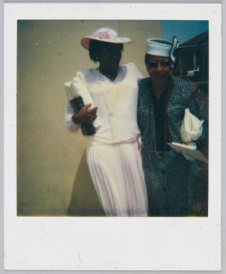 [Two women in formal attire posing with arm around each other, woman on right wears all pink outsite]