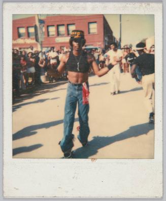 [Young man displaying his abs, groups of people gathered in the background]