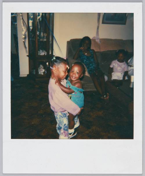 [Little girl holding up toddler girl on her own]