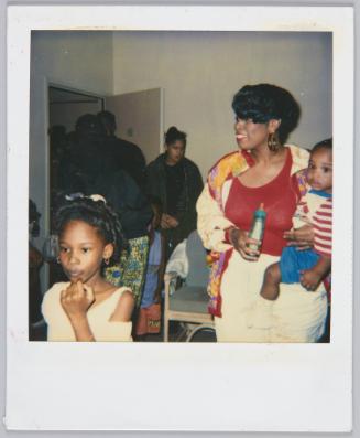 [Woman holding baby on her hip and bottle, little girl stands before her]