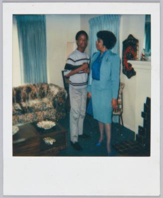 [Women in blue pencil skirt and matching blazer looking at adolescent boy standing next to her]