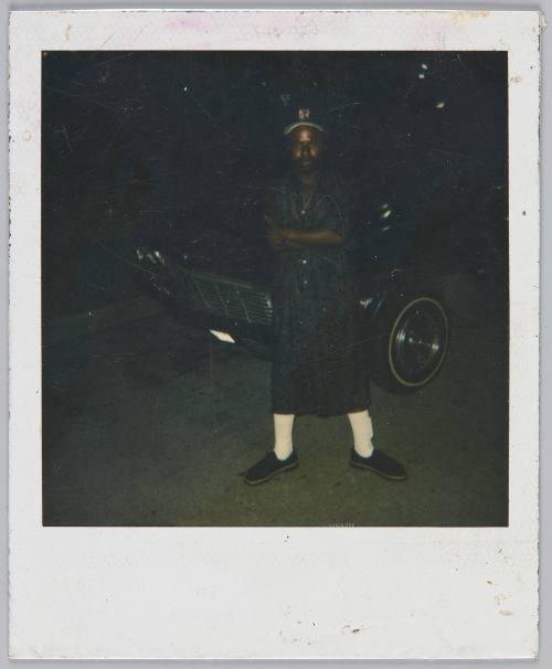 [Underexposed image of man standing parking lot with his arms crossed and wearing bright white sox]