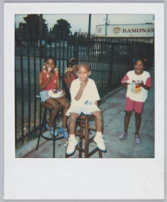 [Three children sitting on wooden stools outdoors, little girl on right wearing a Winnie the Pooh tshirt]