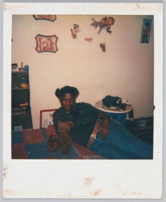 [Girl laying on bed next to brown teddy bear]