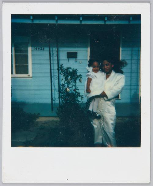 [Woman in white outfit holding toddler girl in white dress and matching hairties]