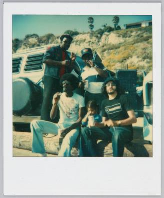 [Group of four men smoking cigarettes with little girl with pigtails sitting in between them]