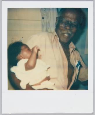 [Elderly man with grey moustache holding infant]