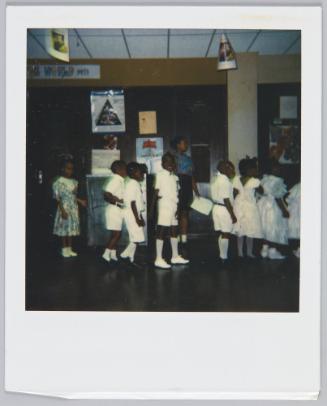 [Group of children dressed in white standing in a line]