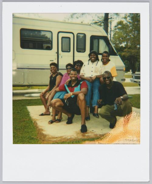 [Groupd of seven gathered on and around picnic table, RV parked in the background]