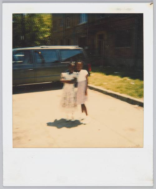 [blurry image of two little girls in dresses standing in parking lot]