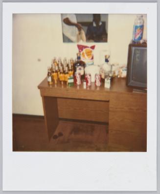 [blurry image of desk covered with beer bottles, Coca Cola cans and bag of chips]