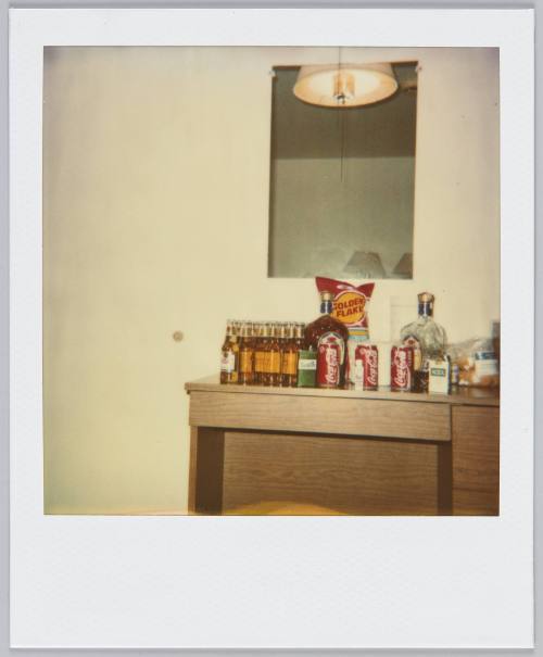 [Desk covered with beer bottles, Coca Cola cans, and bag of chips]