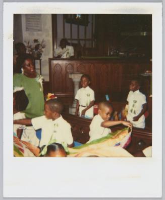 [Four little boys in matching outfits placing streamers on pews]