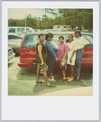 [Group of five women posing with red van behind them]