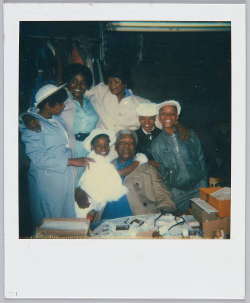 [Group gathering around elderly man sitting at table]