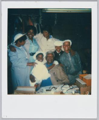 [Group gathering around elderly man sitting at table]