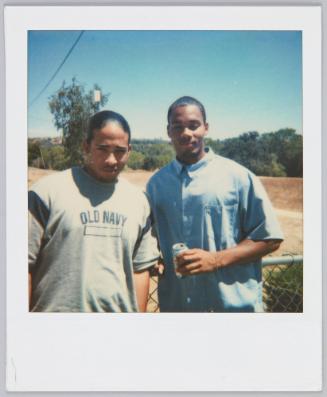 [Young man in Old Navy tshirt standing next to young man holding a can of soda]