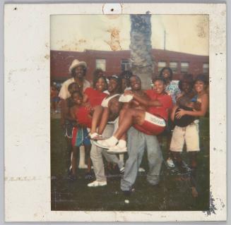 [Large group posing, three men in front row holding three women in their arms]