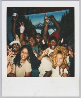 [Group of adults at a party drinking and smoking, two men in the centre are missing teeth]