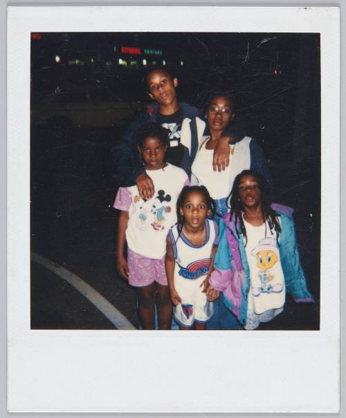 [Adolescent boy and girl with three young girls standing outside at nighttime, children are wearing Disney themed clothing]