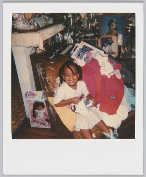 [Young girl smiling and sitting in plastic wrapped chair sitting with boots on her lap]