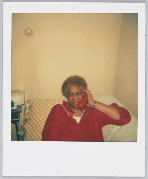 [Woman with red hair sitting on couch talking on a red telephone]