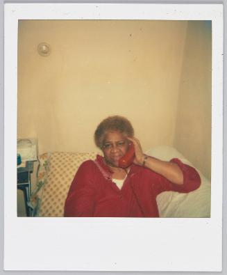 [Woman with red hair sitting on couch talking on a red telephone]