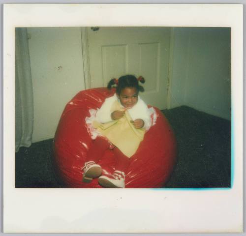 [Girl smiling and sitting in red beanbag chair]
