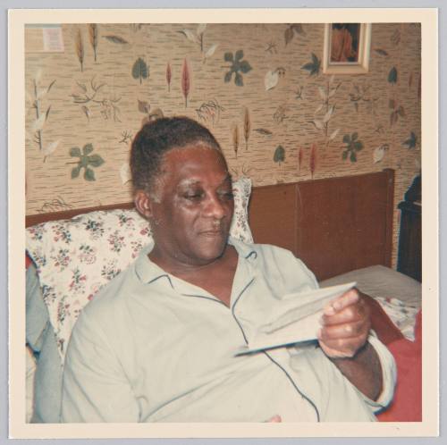 [Man reading letter in bed in his pajamas]
