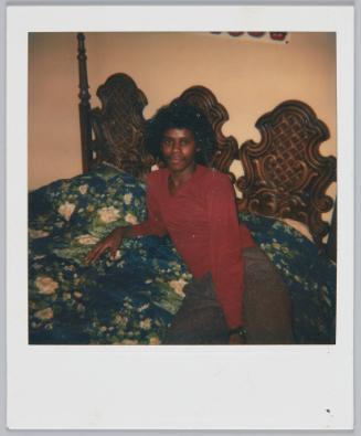 [Young man laying on floral bedspread, wooden headboard]
