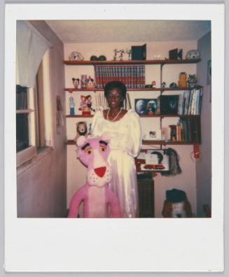 [Woman wearing white gown standing with plush toy of the Pink Panther]
