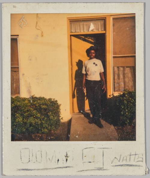 [illeg.] OJ Watts [Adolescent in brimmed hat standing outside of doorway outside, door is painted yellow]