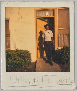 [illeg.] OJ Watts [Adolescent in brimmed hat standing outside of doorway outside, door is painted yellow]