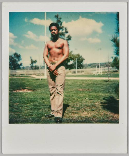[Shirtless man in brown pants standing with hands together in a park during the day]