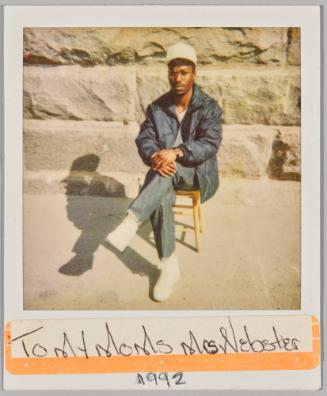 To my moms Mrs Webster 1992 [Man in white baseball cap sitting outside on a wooden stool]