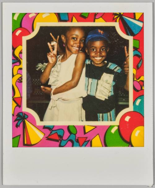 [Two children making "Peace" signs with American money bills attached to their outfits, image surrounded by colourful party themed border]