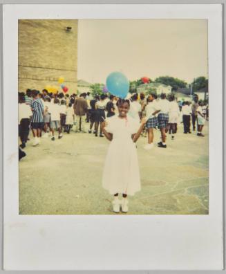 [Girl in white dress with blue balloon, standing outside with more children behind her]